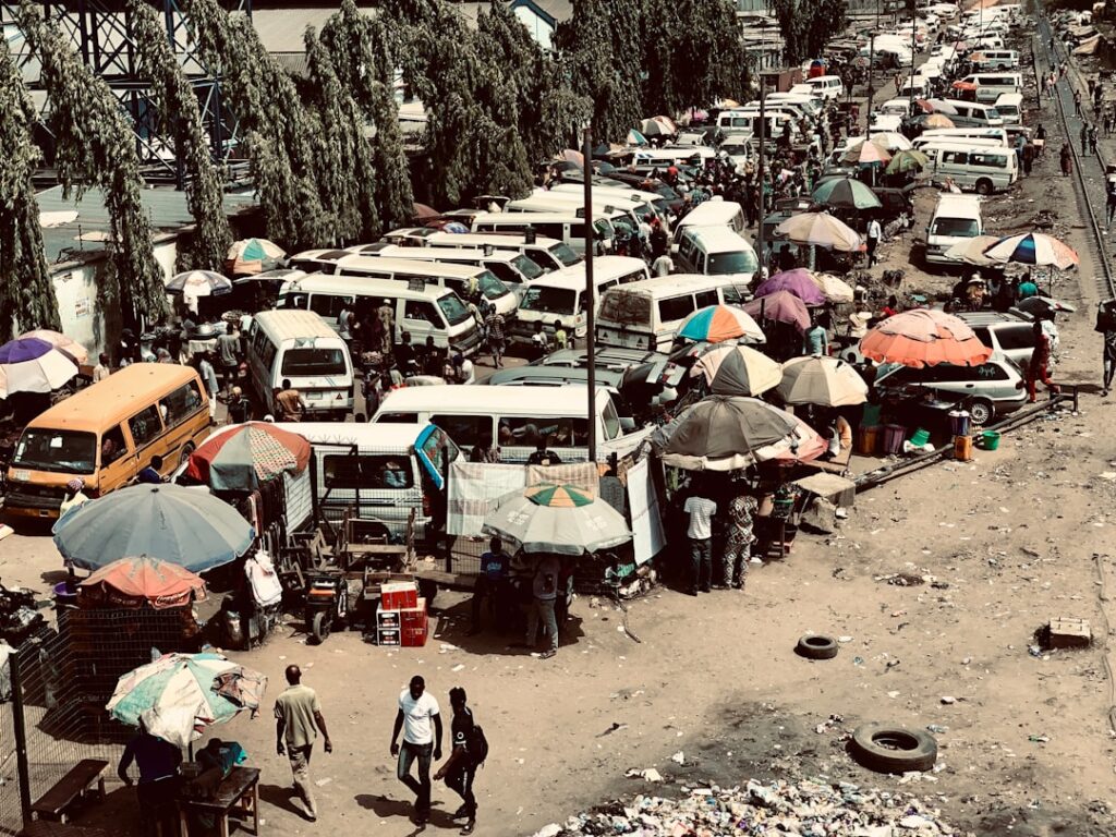 Busy Nigerian market scene with vehicles, traders, and colourful umbrellas representing commerce in Nigeria
